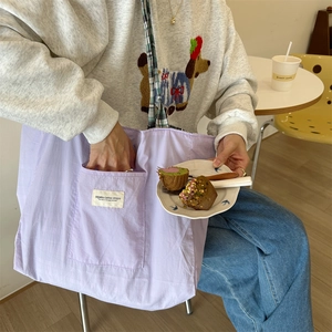 Lavender canvas tote bag with check strap and large front pocket in a cafe setting