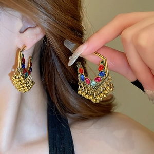 Detail of ethnic phoenix crescent earrings with colorful stones and gold bead tassels