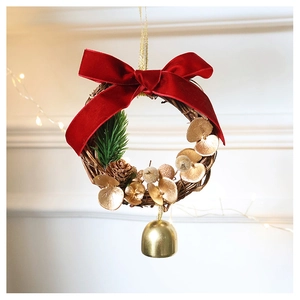 Close-up of a Christmas wreath with a red velvet bow and a shiny golden bell detail