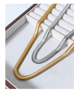 Detail of gold and silver snake bone chain necklaces in a wooden jewelry display case