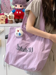 Detail view of purple drawstring tote bag with a cute white bunny pendant charm