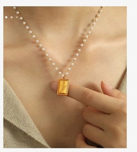 Dettaglio del ciondolo a tulipano dorato e delle perle bianche su collana vintage