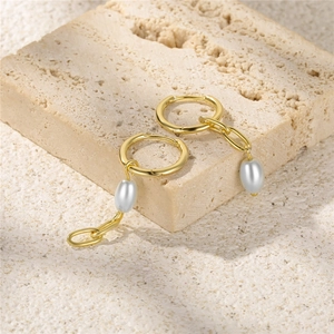 Detail view of S925 silver pearl drop earrings on a textured beige stone background