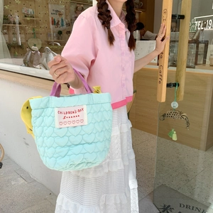 Détail du sac matelassé bleu clair avec motifs de cœur et poignées roses dans un café