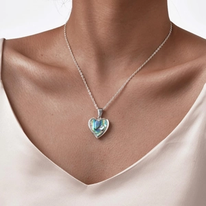 Close-up of heart locket necklace with iridescent shell inlay worn by model