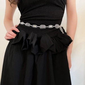 Detail of vintage silver metal waist chain with oval embossed links on black dress