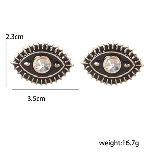 Detailed view of evil eye earrings in gold metal with black enamel and rhinestones
