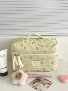 Detailed texture of green quilted cotton makeup bag with purple tulip floral patterns