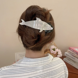 Detail of whale acrylic hair claw clip holding hair in a bun for casual styling