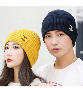 Close-up of yellow and navy knit beanies with Moment of Ambitions patches