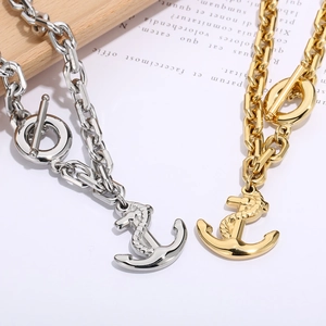Detailed view of silver and gold anchor pendant necklaces with toggle clasp on wood