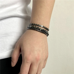 Close-up of three dark gray hematite bracelets with elastic cord on male wrist