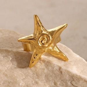 Detailed macro view of gold starfish ring with spiral texture on natural stone