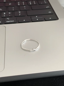 Detail of silver heart-shaped adjustable ring resting on a sleek laptop trackpad surface