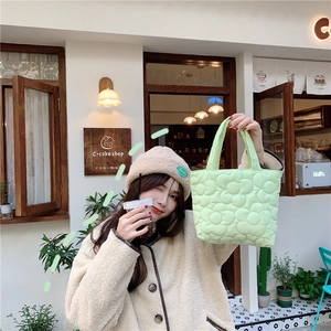 Close-up of quilted floral pattern on a light green padded puffy handbag for moms