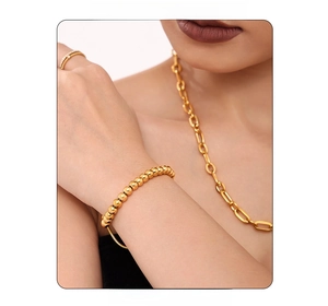 Close-up of 4mm gold beaded bracelet and paperclip necklace worn by a model