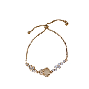 Adjustable gold chain bracelet with zircon stones and yellow oval gem on white background