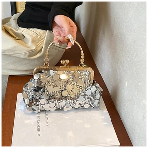 Detailed view of silver sequin evening bag with gold metal handle and ball clasp closure