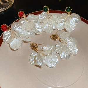 Close-up of petal earrings with crystals and pearl tassels in red, green and amber