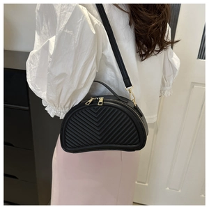 Detail view of black V-quilted leather shell bag with elegant gold dual zipper closure