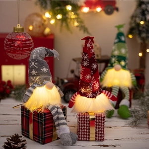 Three glowing Christmas gnomes with knitted hats and plush beards on gift boxes