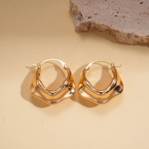 Vue détaillée de boucles d'oreilles créoles dorées texturées sur un support en pierre