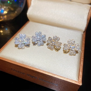 Detail of sparkling clover stud earrings in gold and silver set inside a luxury gift box