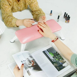 Close-up of pink leather nail footstool with white metal legs on a marble desk