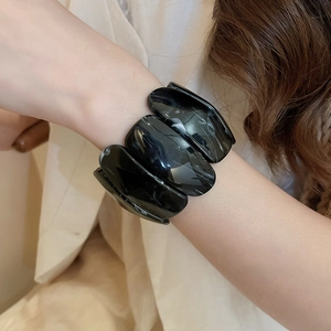 Detail of wide resin bangle featuring black marble texture and polished glossy finish