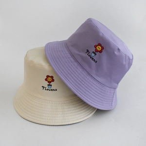Detailed close-up of fruit flower embroidery on beige and purple cotton bucket hats