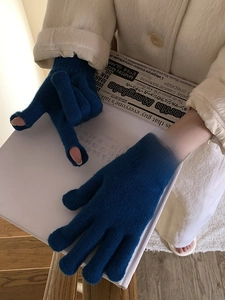 Detail of blue knitted gloves with woven label and tactile ribbed cuffs for winter