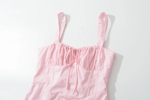 Detail view of pink vintage dress featuring gathered bust and front lace-up ribbon bow