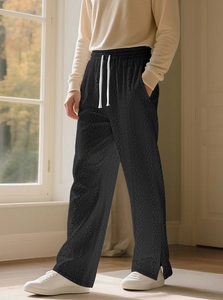 Detail von schwarzer Strickhose mit Zopfmuster, weißem Kordelzug und Textur-Nahaufnahme