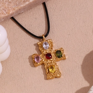 Detail of 18K gold cross pendant with colorful oval gemstones and black cord strap