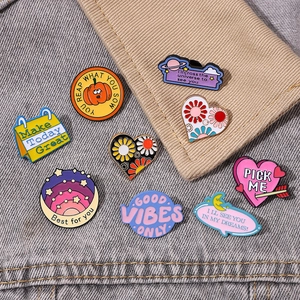 Colorful enamel metal pins with motivational quotes on a classic blue denim background