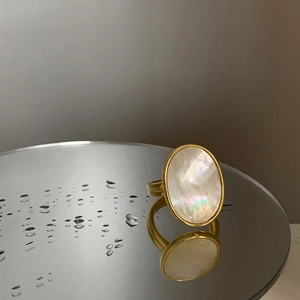 Detail shot of vintage golden ring with iridescent oval mother of pearl on water drops