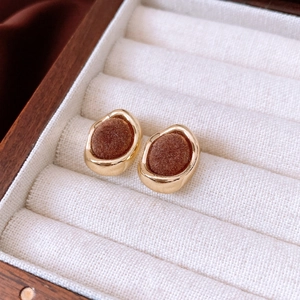 Macro detail of retro gold-rimmed earrings with dark brown flocking in a velvet box