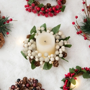 Christmas candle ring with red white berries, pine cones and green leaves on snow