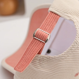 Détail de la boucle métallique réglable sur casquette en velours côtelé beige et rose