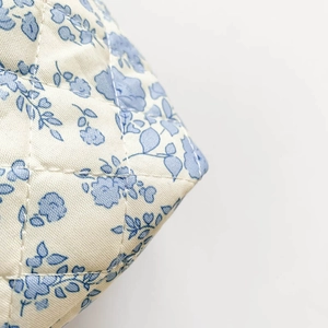 Detail view of quilted cotton fabric with vintage blue floral patterns on a makeup bag