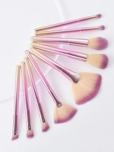 Close-up of 9 professional makeup brushes with pink gradient handles and soft beige bristles