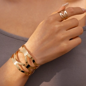 Détail du bracelet et bague ajourés dorés portés sur mannequin montrant la texture