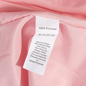 Etichetta di lavaggio su abito in chiffon rosa con 100% poliestere e istruzioni d'uso