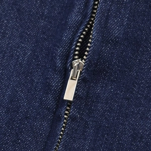Détail macro de la fermeture éclair en métal argenté sur tissu denim bleu foncé