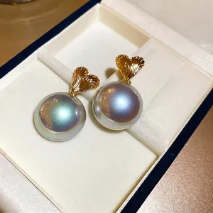 Elegant gold heart earrings with iridescent mabe pearls on a white velvet jewelry box