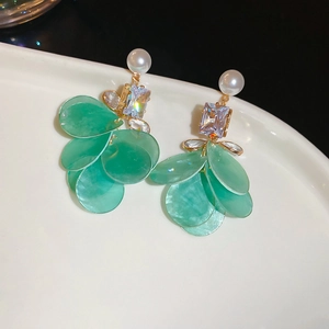 Detailed view of leaf-shaped earrings with pearls, zircons, and green resin tassels