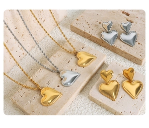 Detailliertes Set aus 18K Gold- und Silber-Herzketten und Ohrringen auf Steindisplay