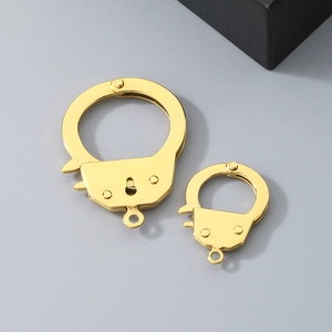 Macro detail of gold stainless steel handcuff-shaped charms in two different sizes