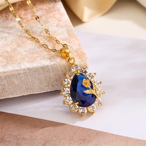 Macro shot of blue teardrop pendant with micro-pave crystals and gold rose detail