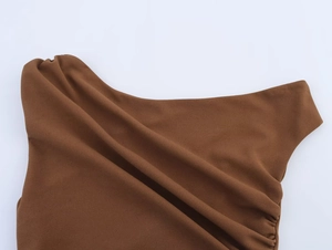 Détail macro du tissu texturé marron avec encolure plissée et design des épaules